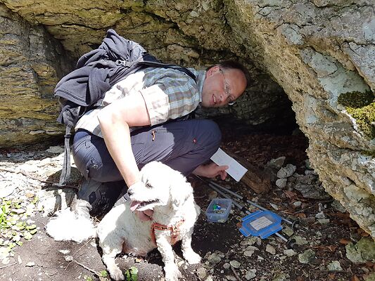 Ein Mann mit Hund beim Auffinden eines Geocaches.