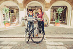 Auf dem Bild sind zwei Frauen mit Fahrrädern zu sehen. Sie stehen vor dem Gebäude der Tourist-Information.
