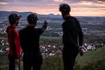 Drei RadfahrerInnen stehen mit dem Rücken zur Kamera und blicken über das Tal